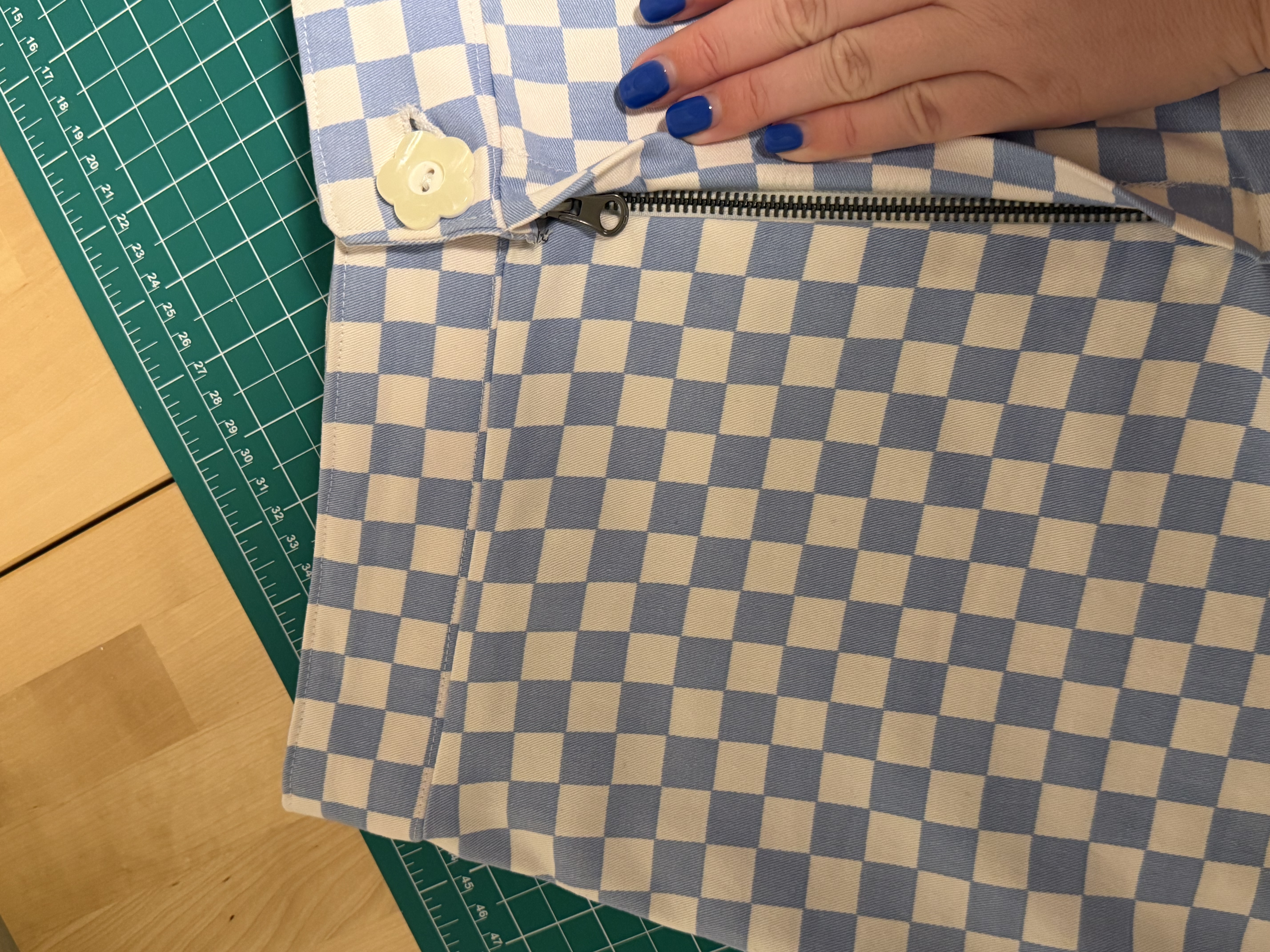 Close up of the zipper guard flap and button, checks lined up perfectly across it